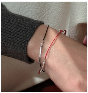 Close-up of minimalist S925 silver Morse code bracelets in red and black silk cords