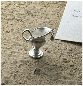 Macro detail of matte S925 sterling silver water bottle pendant on natural sand