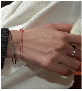 Detail of minimalist red and black string rings with small silver beads on hand