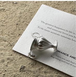 Close-up of matte S925 sterling silver pitcher pendant with a tiny hanging water droplet