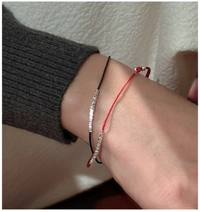 Detail of red and black minimalist cord bracelets with silver beads on a model's wrist