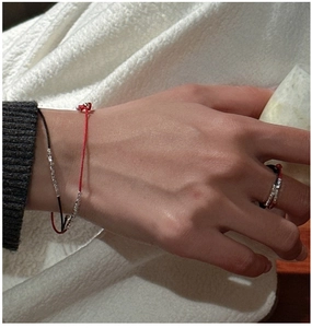 Detail view of woven red and black cord bracelets with silver beads on a wrist