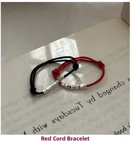 Close-up of minimalist black and red braided rope rings with silver beads on a book