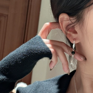Elegant S925 sterling silver drop earrings with black beads worn by a model in soft light