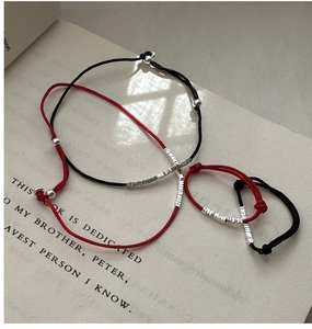 Close-up of minimalist red and black woven cord bracelets with silver metal beads