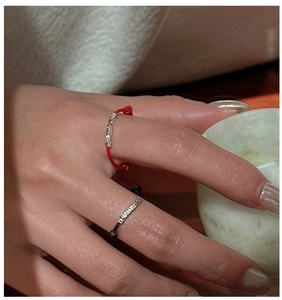 Detail of red and black cord rings with silver beads on a hand for a minimalist aesthetic