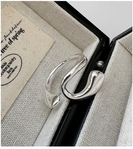 Macro view of minimalist silver wave ring with liquid metal texture in a jewelry box