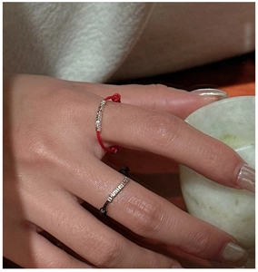 Detail of adjustable red and black string rings with small silver sliding beads on finger