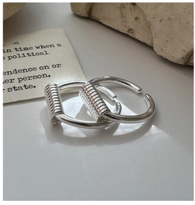 Detail view of silver S925 rings featuring unique metal wire wrap and polished finish