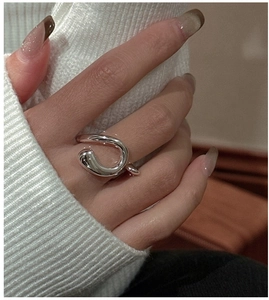 Close-up of a high-shine silver liquid metal style ring on a hand with knit sleeves