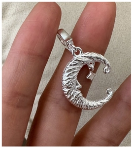 Detailed close-up of a silver crescent moon face pendant with a small hanging star charm