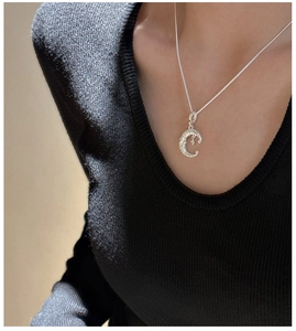 Macro detail of silver crescent moon pendant with vintage texture on a delicate chain