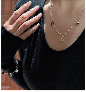 Detail view of S925 silver necklace and bracelet set with gold beads on black fabric