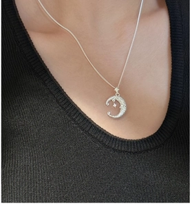 Detail view of S925 sterling silver crescent moon and star pendant on a black sweater