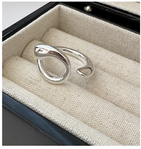 Detail of artistic flowing silver ring on black jewelry box with minimalist metal texture