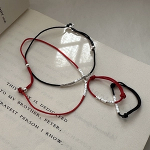Minimalist red and black woven cord bracelet set with silver beads on a vintage book