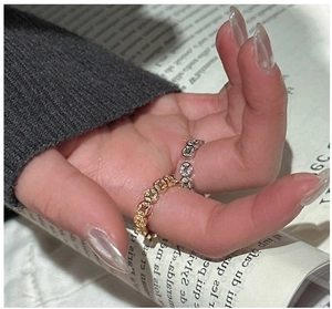 Macro view of gold and silver hollowed coin pattern stackable rings on a hand
