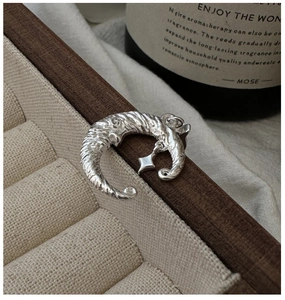 Macro shot of silver crescent moon and star pendant with hammered texture on wood
