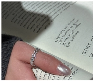 Detail of silver vintage coin ring with zircon stones worn on thumb against book background