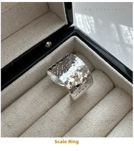 Détail macro d'une bague large en argent S925 avec texture d'écailles dans un écrin à bijoux