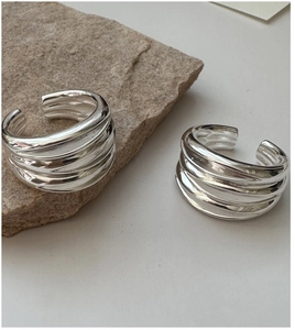 Detailed close-up of multilayer wavy silver rings displayed on natural stone texture