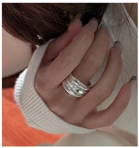 Macro detail of silver S925 multi-layered textured ring on finger showing modern thickness