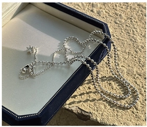Macro view of silver bead chain necklace with six-prong set cubic zirconia pendant