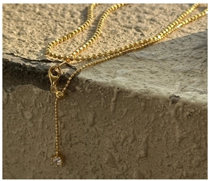 Macro view of adjustable gold bead chain necklace with lobster clasp and zircon pendant