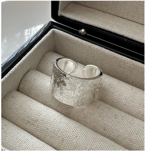 Détail macro d'une bague large en argent S925 avec texture martelée dans une boîte cadeau
