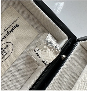 Détail macro d'une bague large en argent S925 avec texture martelée dans son écrin