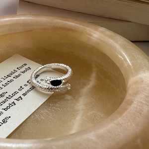 Vintage S925 sterling silver snake ring with black gemstone on a decorative stone bowl