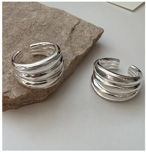 Macro shot of polished S925 sterling silver multi-layer wavy rings on stone background