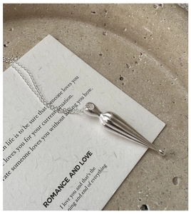 Macro view of a polished silver teardrop pendant on a minimalist thin chain necklace