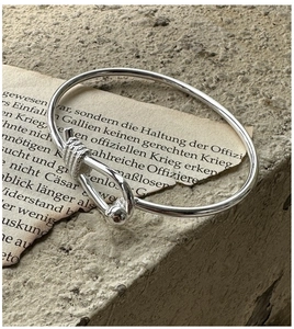 Detail of S925 silver knotted bangle with buckle clasp on vintage paper background