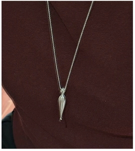 Macro detail of the polished silver teardrop pendant on a minimalist S925 necklace
