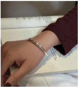 Close-up of a minimalist silver open bangle worn on wrist with elegant lifestyle background