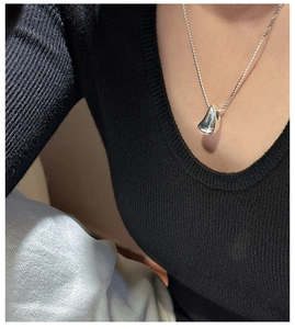 Gros plan du pendentif goutte en argent S925 poli sur un mannequin vêtu de noir
