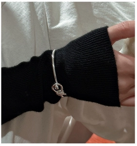 Detail of S925 sterling silver knotted hollow tube bracelet on woman's wrist