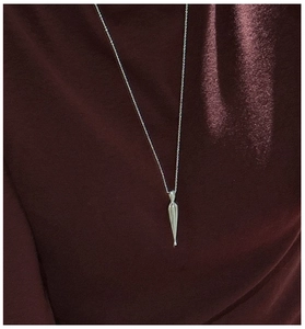 Detailed close-up of polished silver teardrop pendant necklace on dark textured fabric