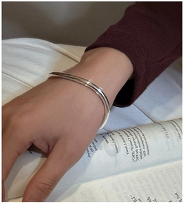 Minimalist S925 sterling silver smooth bangle worn on wrist against a magazine background