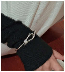 Close-up of S925 silver hollow horseshoe knot bracelet with spiral texture on a wrist