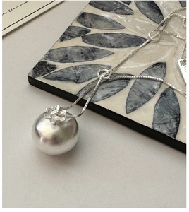 Vue macro du pendentif boule en argent S925 avec détail floral délicat sur l'attache