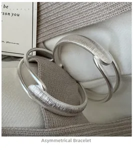 Detail of S925 sterling silver bangle with brushed texture and irregular double-line design