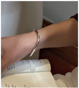 Close-up of minimalist wave-shaped S925 sterling silver cuff bracelet with mirror finish