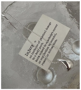 Gros plan du pendentif goutte d'eau en argent poli avec sa chaîne délicate sur verre