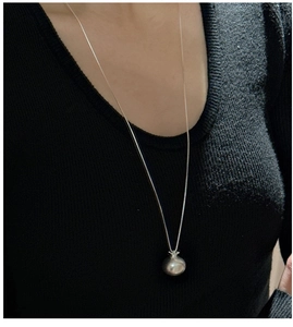 Gros plan d'un collier pendentif grenade en argent 925 sur un pull noir
