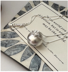 Détail macro du pendentif boule en argent S925 avec texture mate et petite fleur