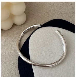 Close-up of polished S925 sterling silver minimalist open bangle on a display pad