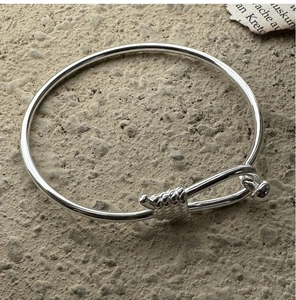 Macro detail of silver minimalist hollow tube bangle with spiral twist and hook clasp