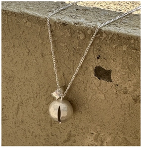 Macro detail of silver necklace with textured sphere pendant on stone background